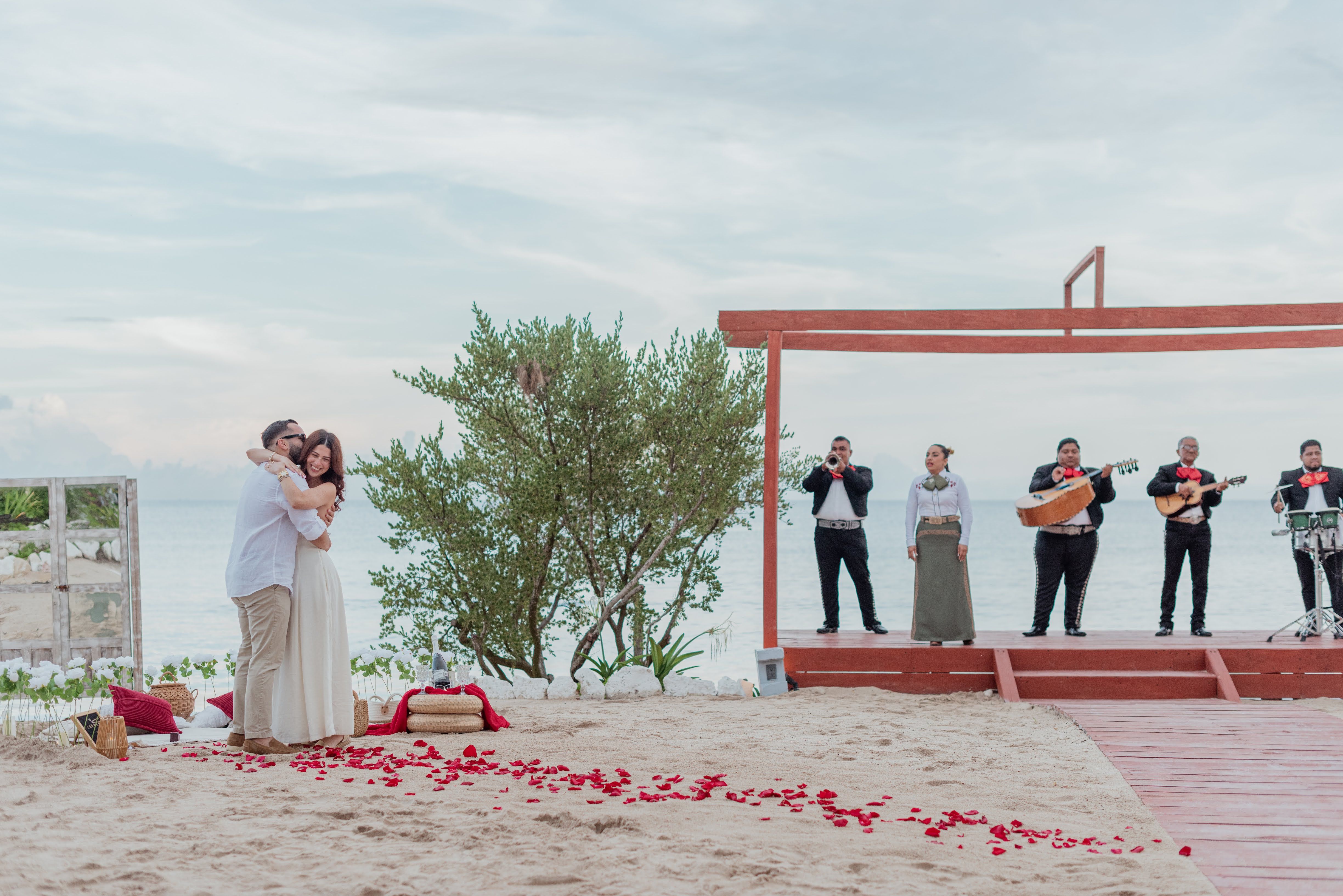 Couple embracing on a pristine white-sand beach in Akumal after a surprise proposal, surrounded by tropical palm trees and turquoise Caribbean waters.