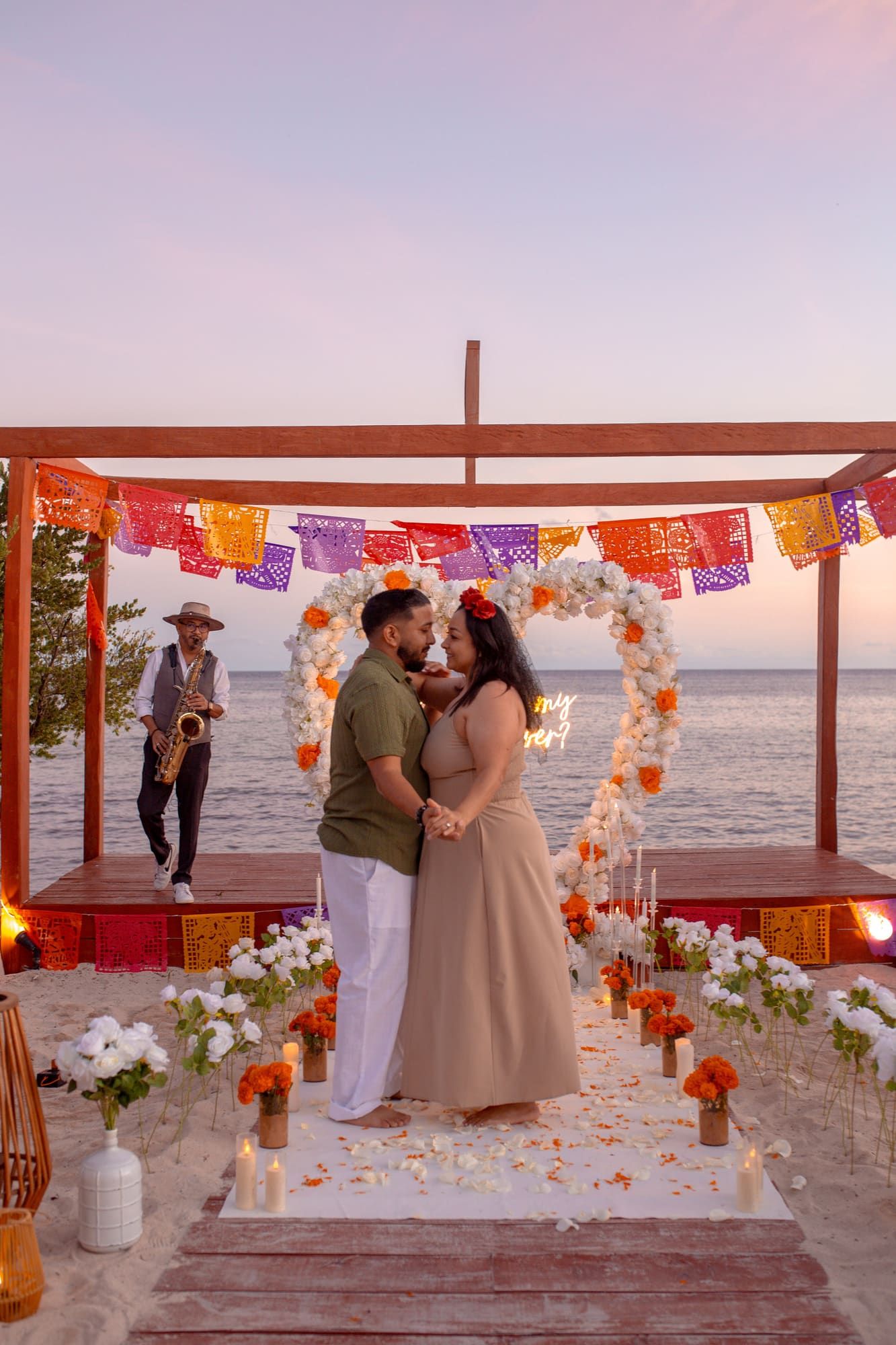 Detailed view of a sunset beach proposal setup in Cancun with a custom 'Marry Me' sign, fresh flowers, and a chilled bottle of premium champagne.