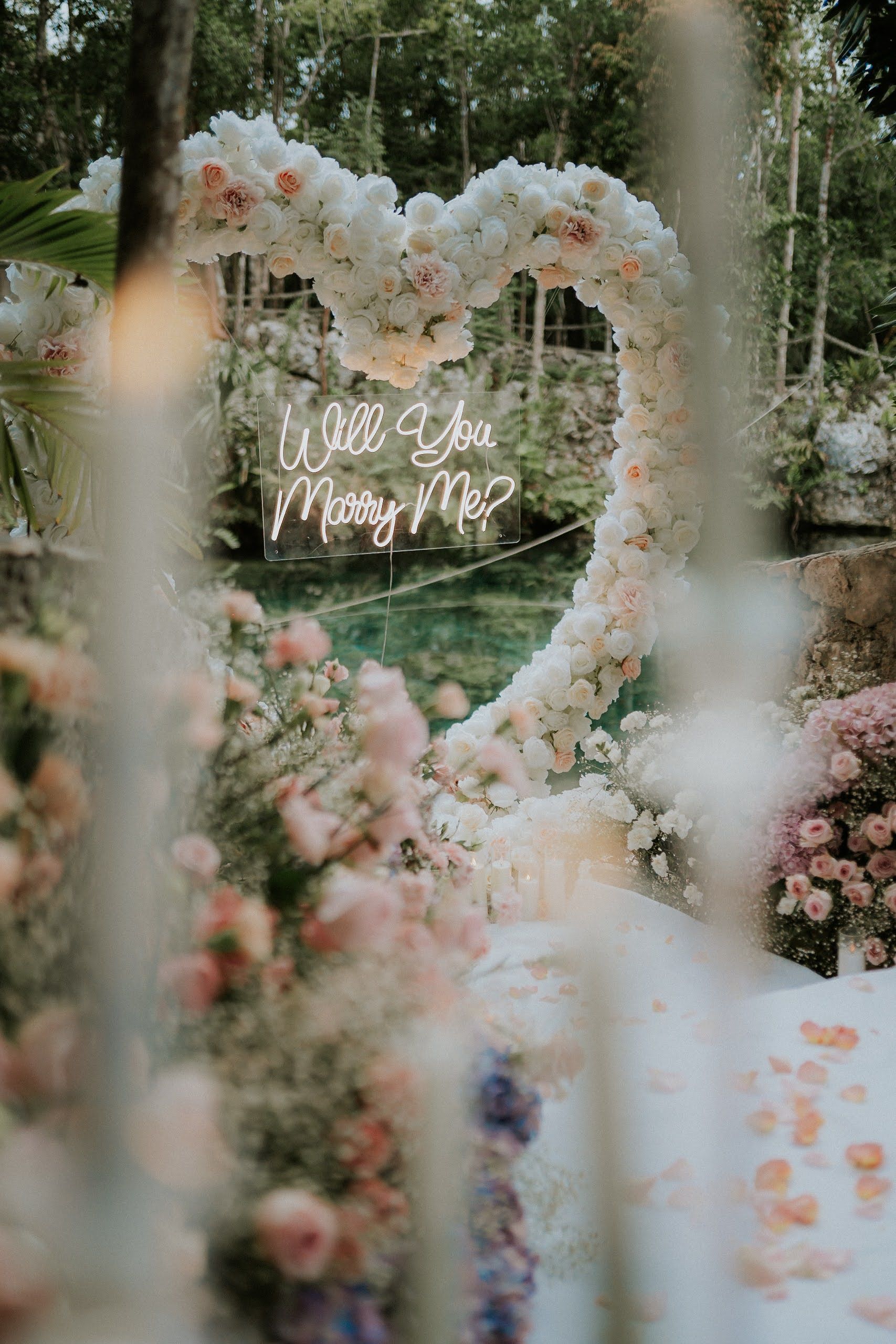 Magical cave proposal in Playa del Carmen with a natural beam of sunlight acting as a spotlight on the floral heart arch and the happy couple.