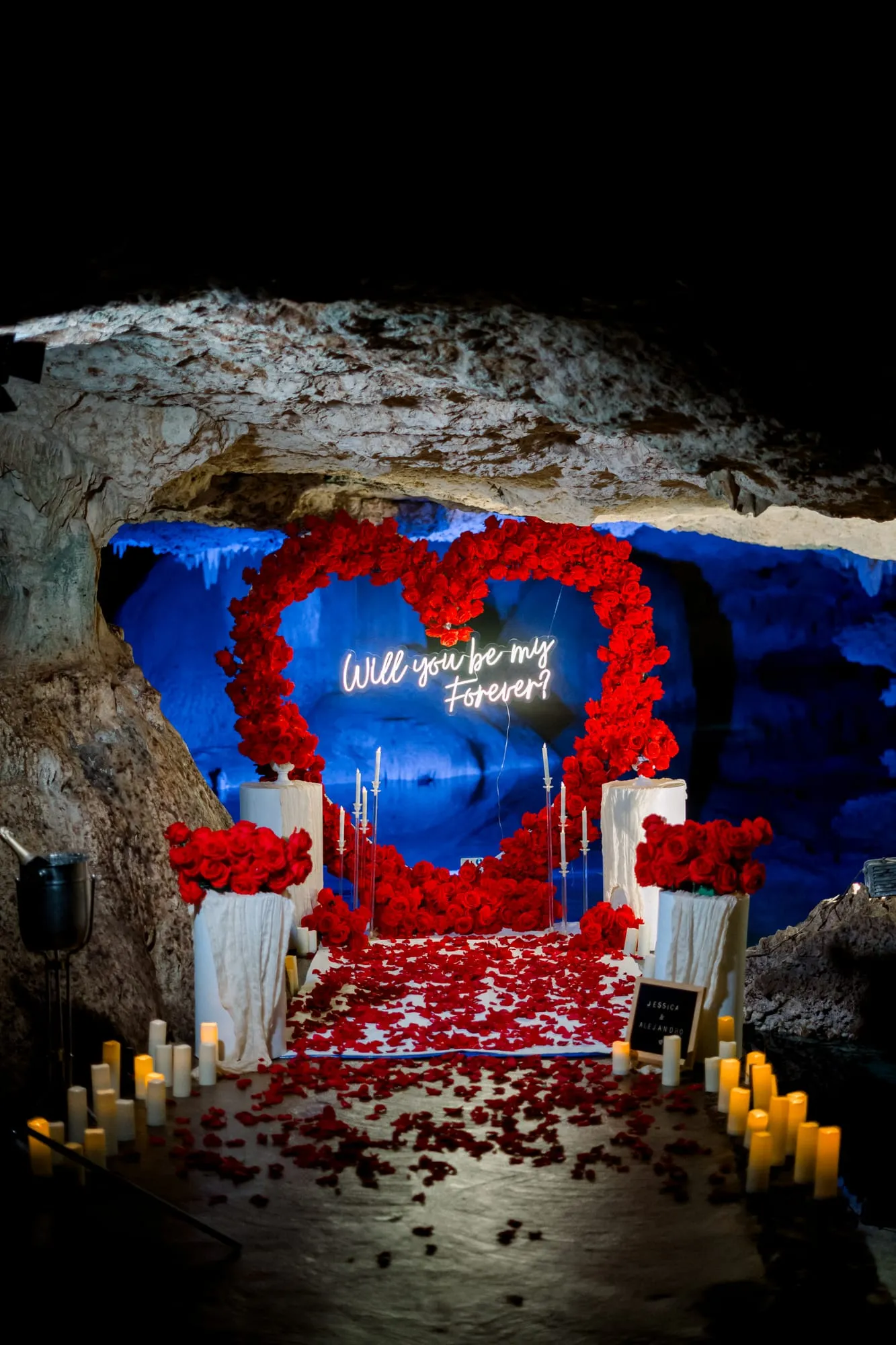 Montaje de propuesta con rosas rojas y velas dentro de una cueva de cenote en Riviera Maya
