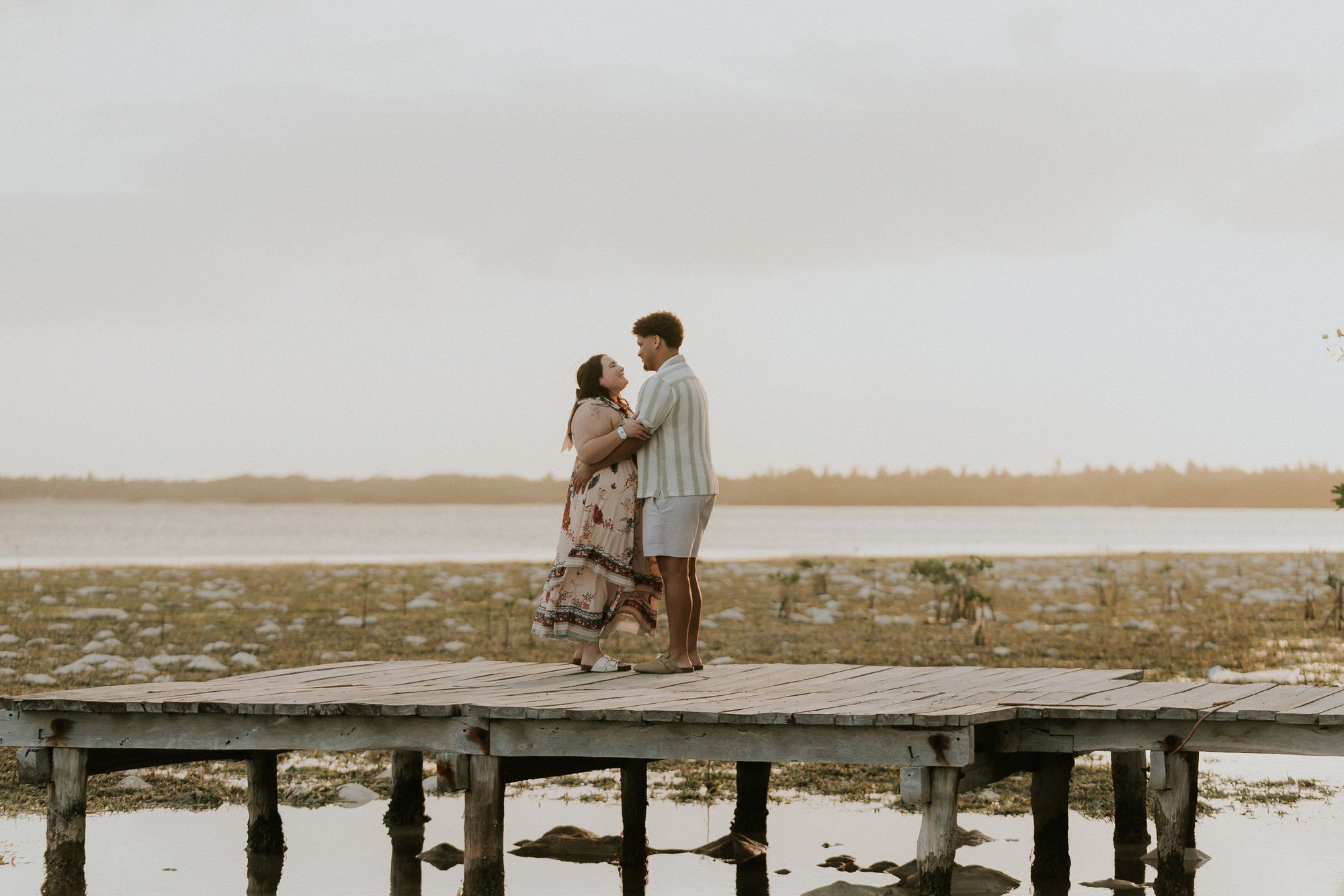 Happy couple celebrating their engagement on a private yacht deck in Tulum with a panoramic view of the Caribbean shoreline.