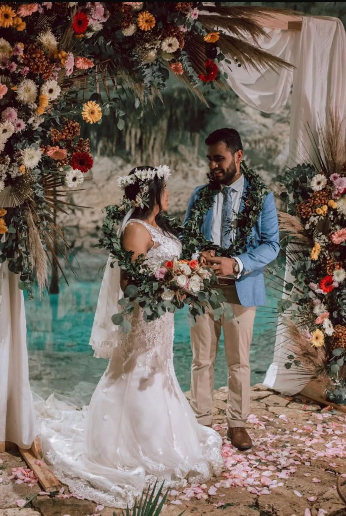 Couple beneath a floral arch during a cenote wedding